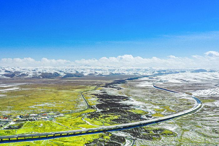 久馬高速與連綿雪山同框 似巨龍穿梭廣袤草原